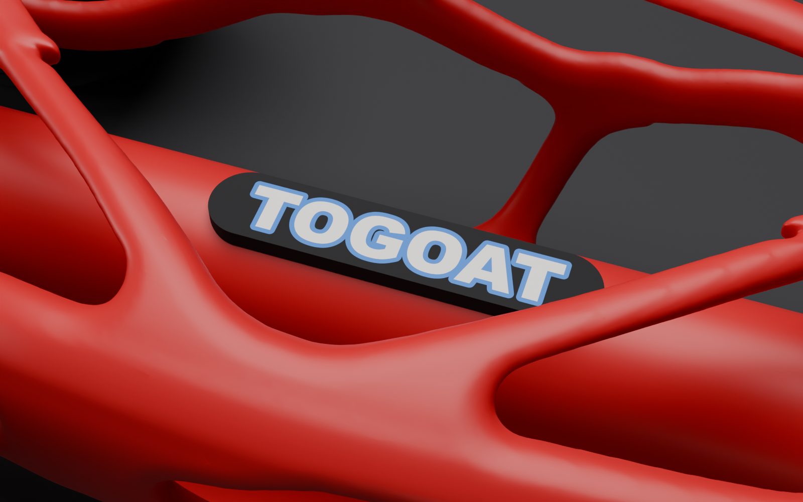 Close render of the TOGOAT badge: white letters with a thin blue outline inlaid in a black plate on a red tube.